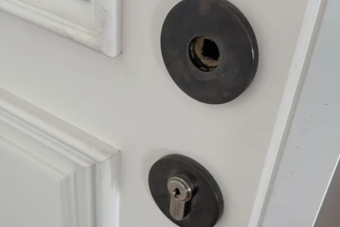 Puerta blanca con dos cerraduras, una de ellas con el bombín desmontado